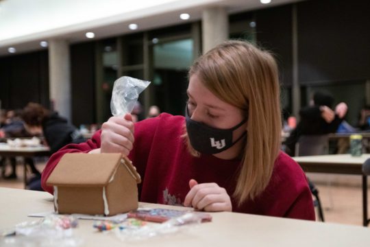 Masked student decorates gingerbread house