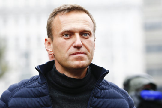 White man with short hair in jacket with turtle neck and puffy coat looks at camera.